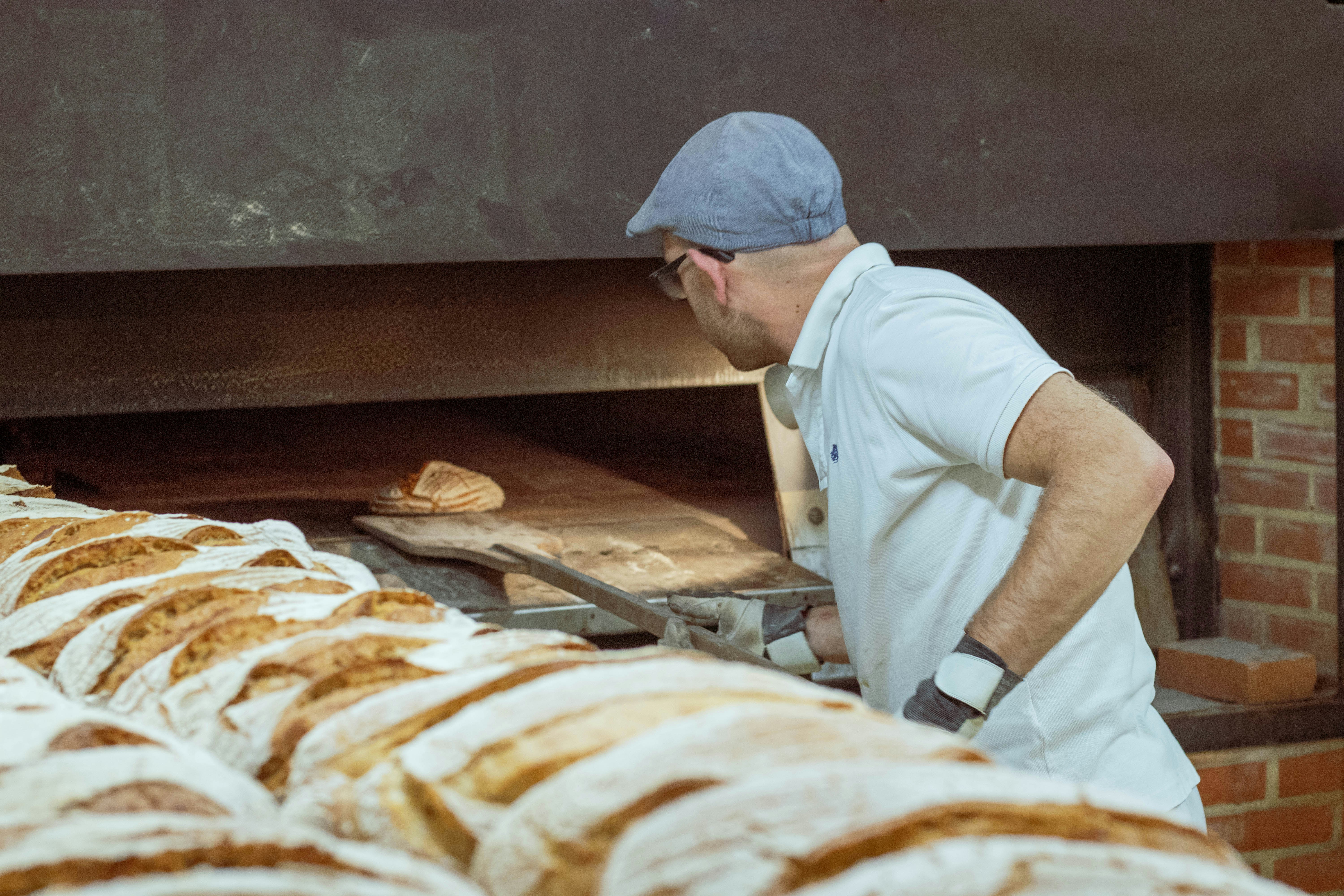 Boulanger sortant une fournée de pains de son four artisanal