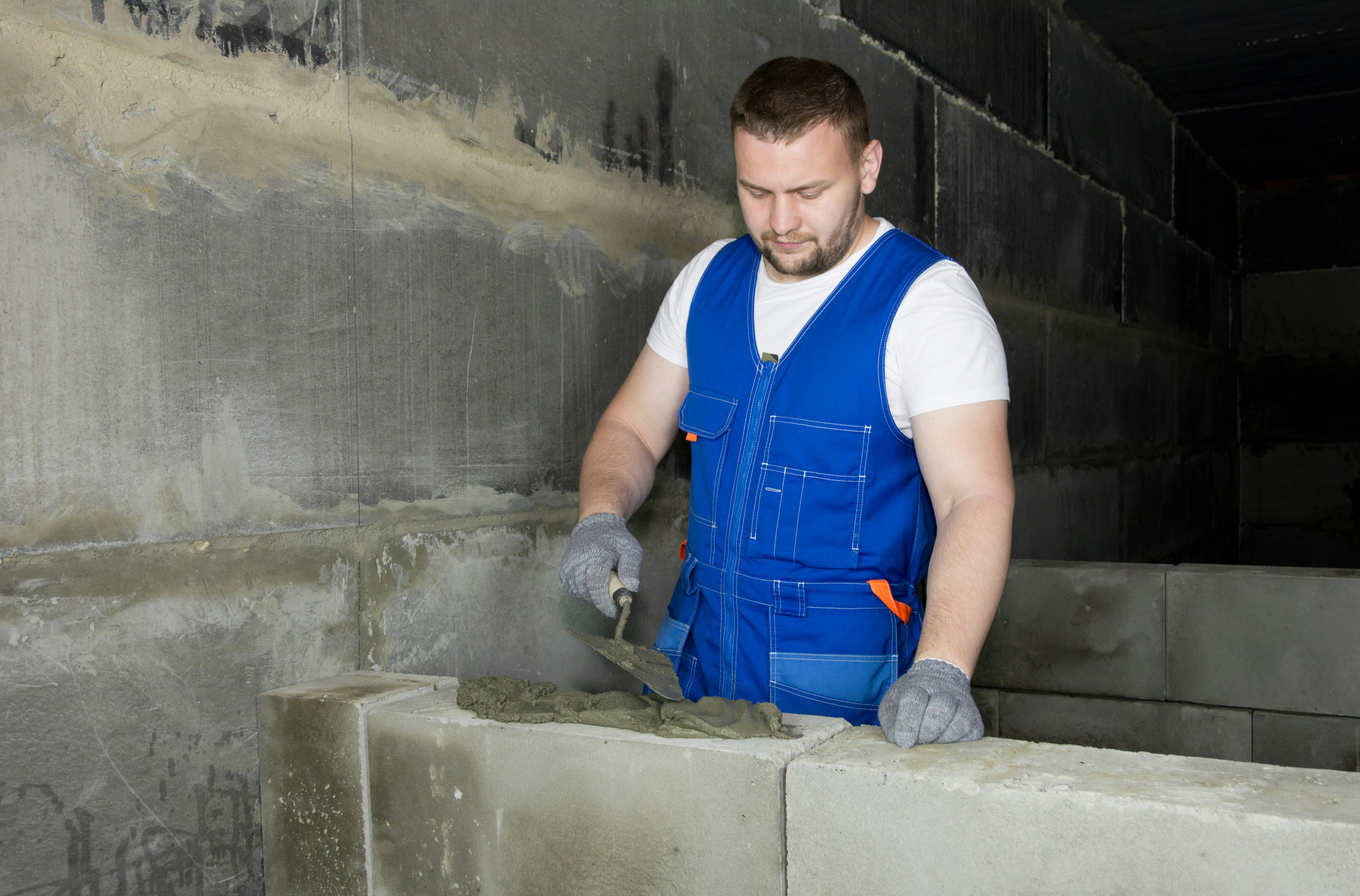 Maçon montant un mur en parpaings sur un chantier de construction